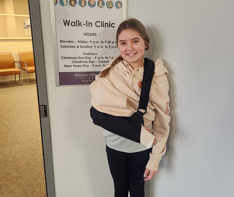 Big sister with sling smiling in front of Waverly Walk in Clinic