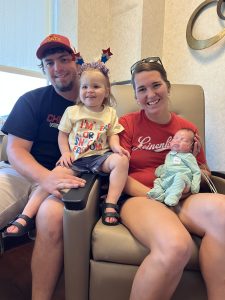 The Zweibohmer family smiling together at home—mom, dad, big sister Mya holding Max, now strong and thriving.